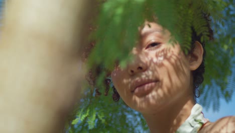 Latina-red-hair-girl-facial-close-up-at-a-park-with-leaves-of-a-tree-in-the-foreground