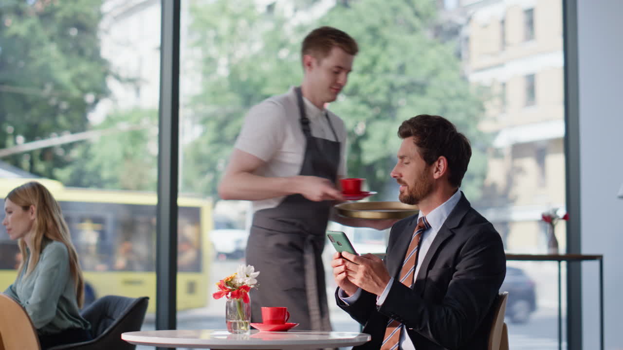 Smiling executive reading cellphone message sitting cafeteria. Relaxed man break