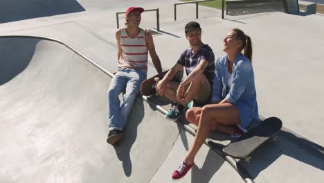 Happy-caucasian-woman-and-two-male-friends-sitting,-laughing-and-spending-time-together-on-sunny-day