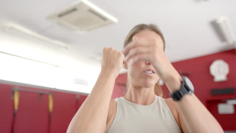 joven mujer caucásica toma una respiración profunda en un entorno de gimnasio en forma