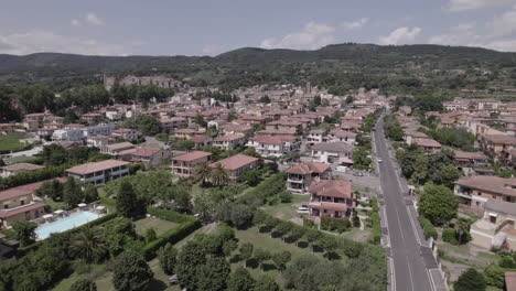 drone shot flying over lake bolsena in italy coming from the water into the old medieval city with a castle and old buildings on the hill on a sunny day log