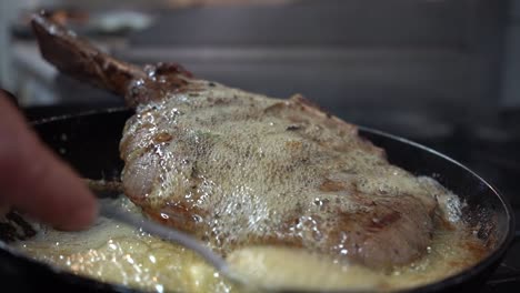 filete de ternera asada en una sartén con el chef vertiendo mantequilla caliente sobre él