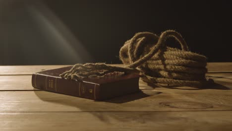 religious concept shot of old bible on wooden table with rope