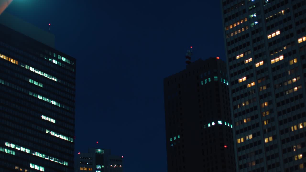 Ripresa scorrevole dal basso di grattacieli nel quartiere finanziario di Tokyo. Panorama del cielo e paesaggio urbano di sera.