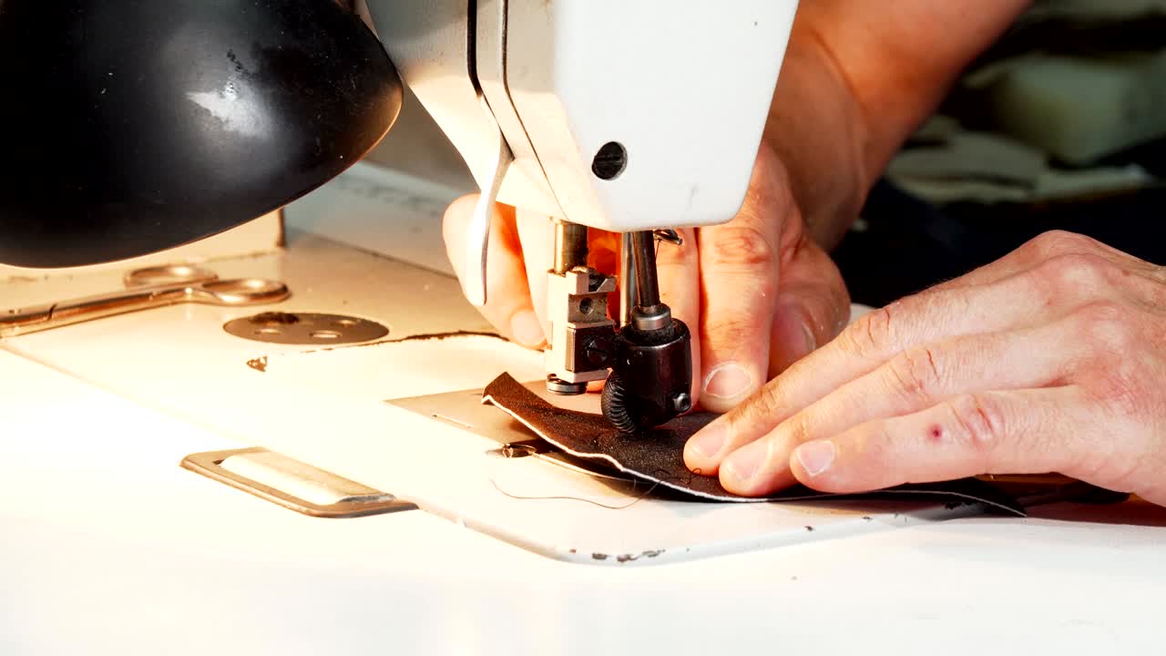 zapatero usando una máquina de coser de época en su taller