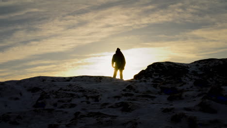 Silhouette-shot-of-a-hiker-enjoying-the-sunrise-at-the-peak-of-Lovstakken,-Norway