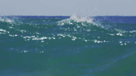 slow-motion view of a sunrise wave rolling across the ocean surface filmed from inside the water, emphasizing the wave's translucency and motion