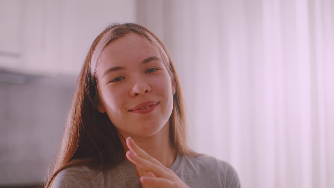Happy young lady smiling brightly, expressing joy and contentment with natural charm, cheerful expression captured in soft indoor light, radiating positivity and youthful confidence