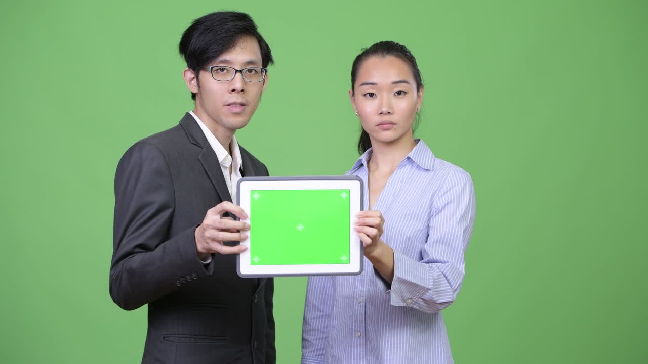 Young Asian business couple showing digital tablet together