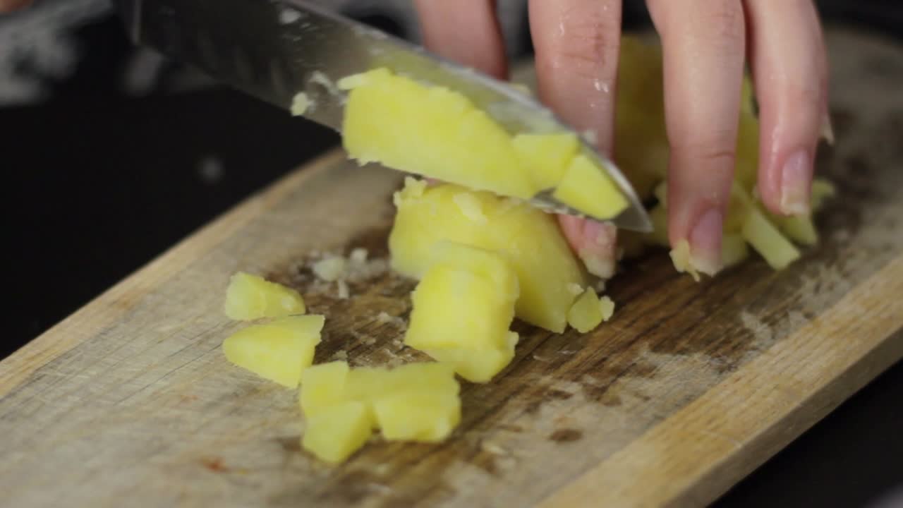 persona mano con cuchillo afilado rebanar patata hervida en tablero de madera