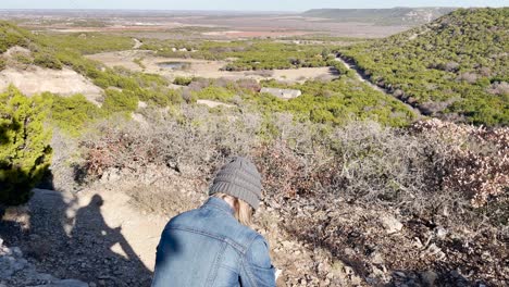girl sitting on a rock on a cliff reading a book