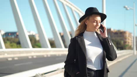 young woman talking on mobile phone on bridge in sunlight