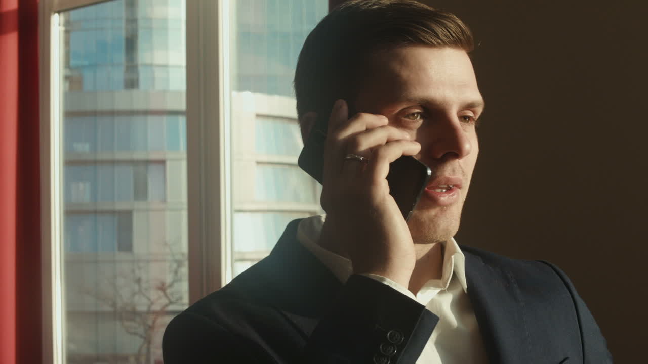 슈트를 입은 남자가 전화로 얘기하고 있다.