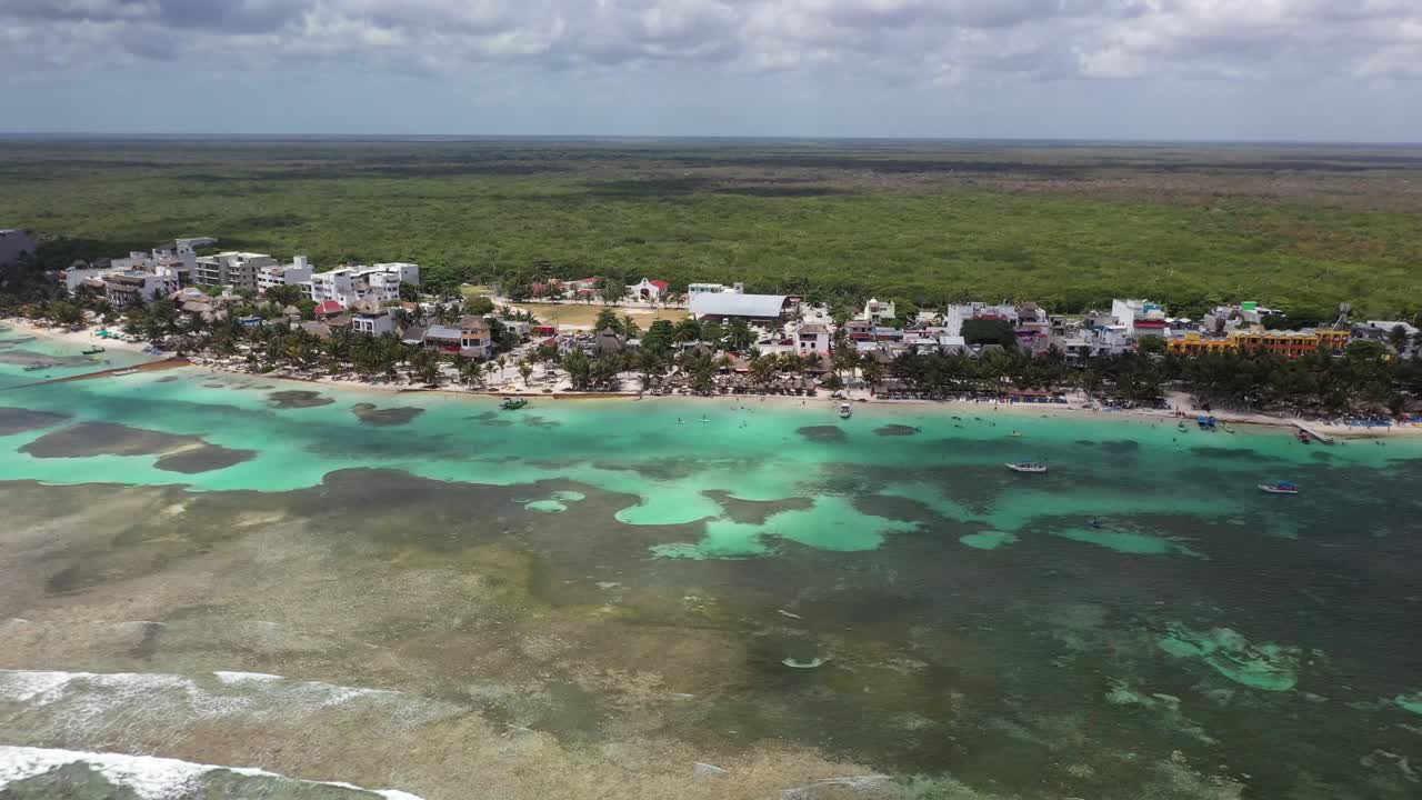 Impresionante vista aérea de Bacalar, México, con aguas cristalinas de laguna turquesa, playa bordeada de palmeras y cabañas con techo de paja. Escena de paraíso tropical con gente disfrutando de la costa caribeña