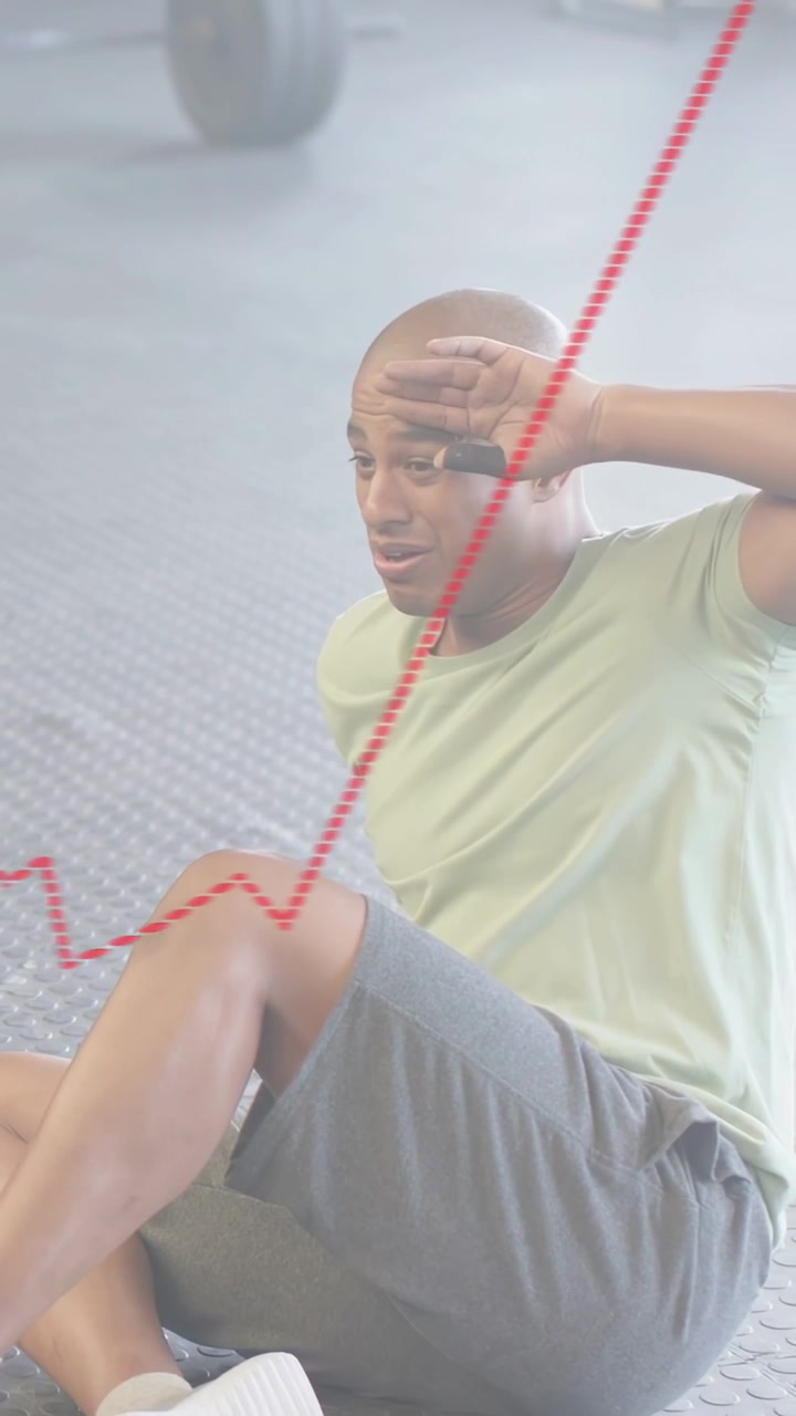 Video verticale: Uomo che si siede sul pavimento della palestra dopo una serie di esercizi, con una freccia rossa animata che sale a indicare lo sforzo.
