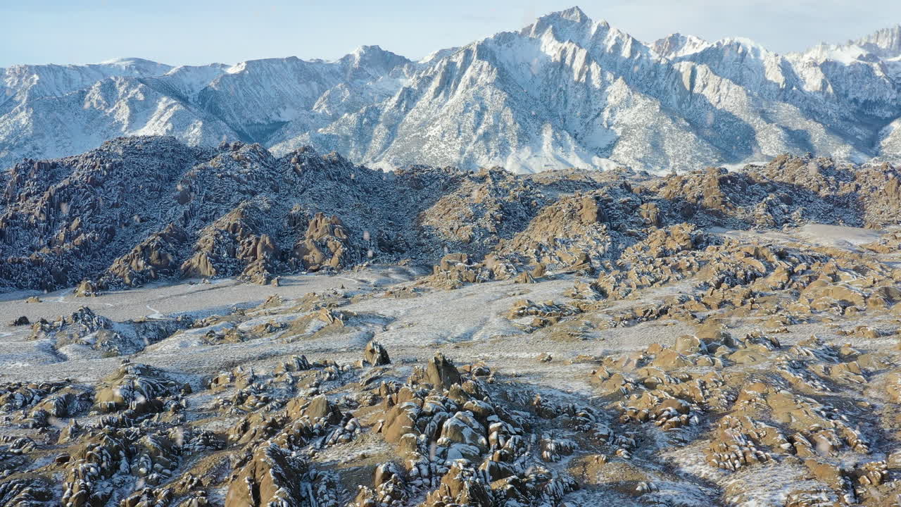 Maestoso paesaggio montano durante l'inverno mentre nevica, vista aerea in allontanamento
