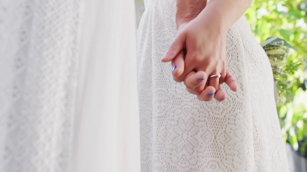 다양한 여성 커플이 손을 잡고 정원에서 꽃을  ⁇ 고 있습니다.