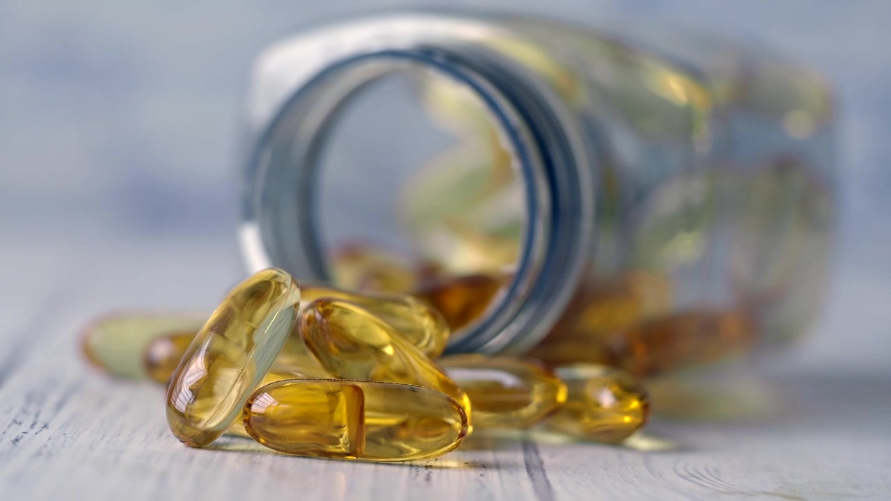 Capsule di olio di pesce Omega-3 rovesciate da una bottiglia di vetro