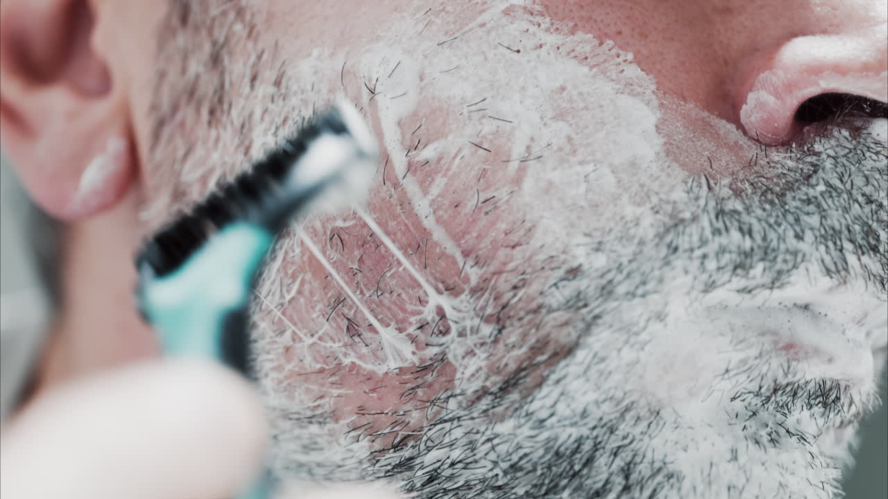 Primo piano di un uomo che si rade la barba con un rasoio