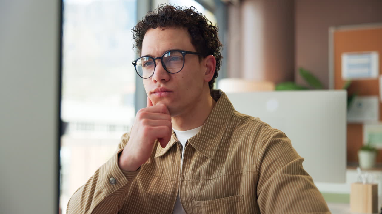 Young Man with Glasses Thinking and Concentrating in Office