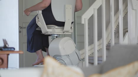 Woman-sitting-on-stairlift-going-down-stairs-of-house