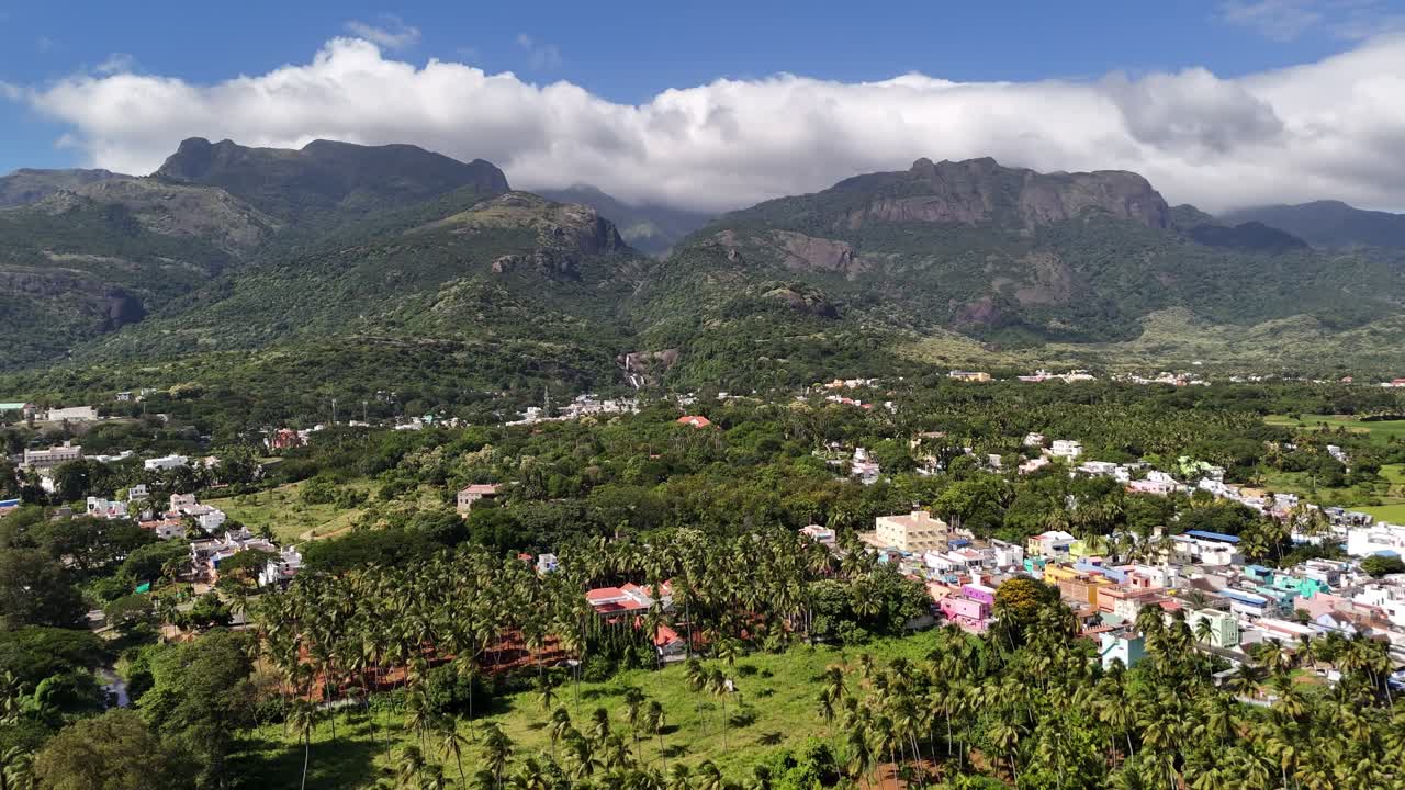 A mesmerising aerial view of a lush South Indian town, Courtallam, nestled at the foothills of the Western Ghats, surrounded by dense greenery and towering mist-clad mountains