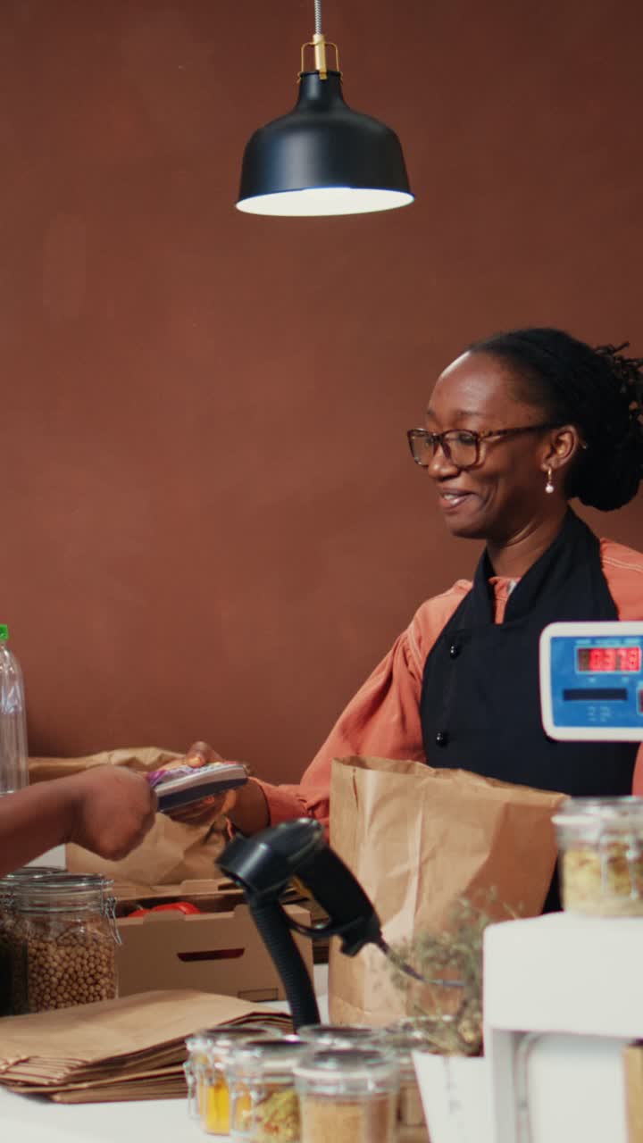 Vertical Video African american buyer paying with card at pos in eco store