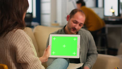 mujer gerente hablando con un compañero de trabajo sosteniendo una tableta con pantalla verde