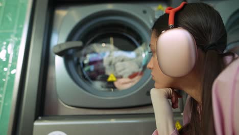 Young woman leaning over a washing machine at a laundromat