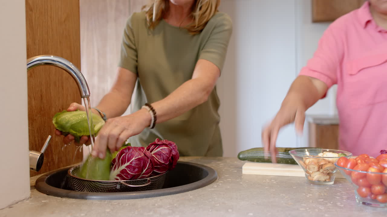 Washing fresh vegetables in kitchen sink, woman preparing healthy meal together, at home