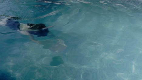 Eine-Schlanke-Junge-Frau,-Die-In-Einem-Swimmingpool-Unter-Wasser-Schwimmt