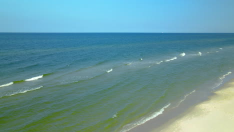 Few-people-on-white-sand-Beach-in-Osetnik,-Poland,-during-the-Covid-19-pandemic-early-autumn-2020,-Drone-Slowly-flying-towards-the-baltic-sea