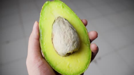 las manos abren cuidadosamente un aguacate maduro, revelando su carne verde cremosa