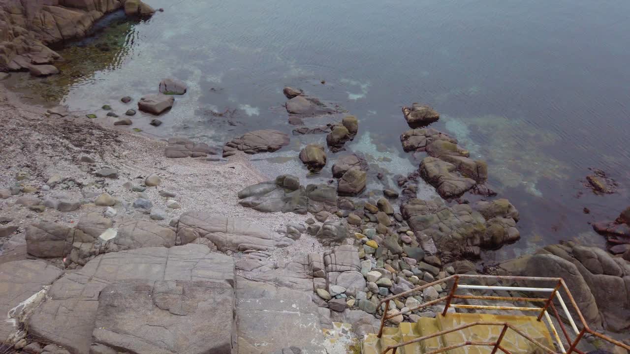 Vista panoramica della costa rocciosa del Mar Nero. Mare calmo, pietre nell'acqua, scale che conducono alla spiaggia a Sozopol, Bulgaria. Panoramica a sinistra.