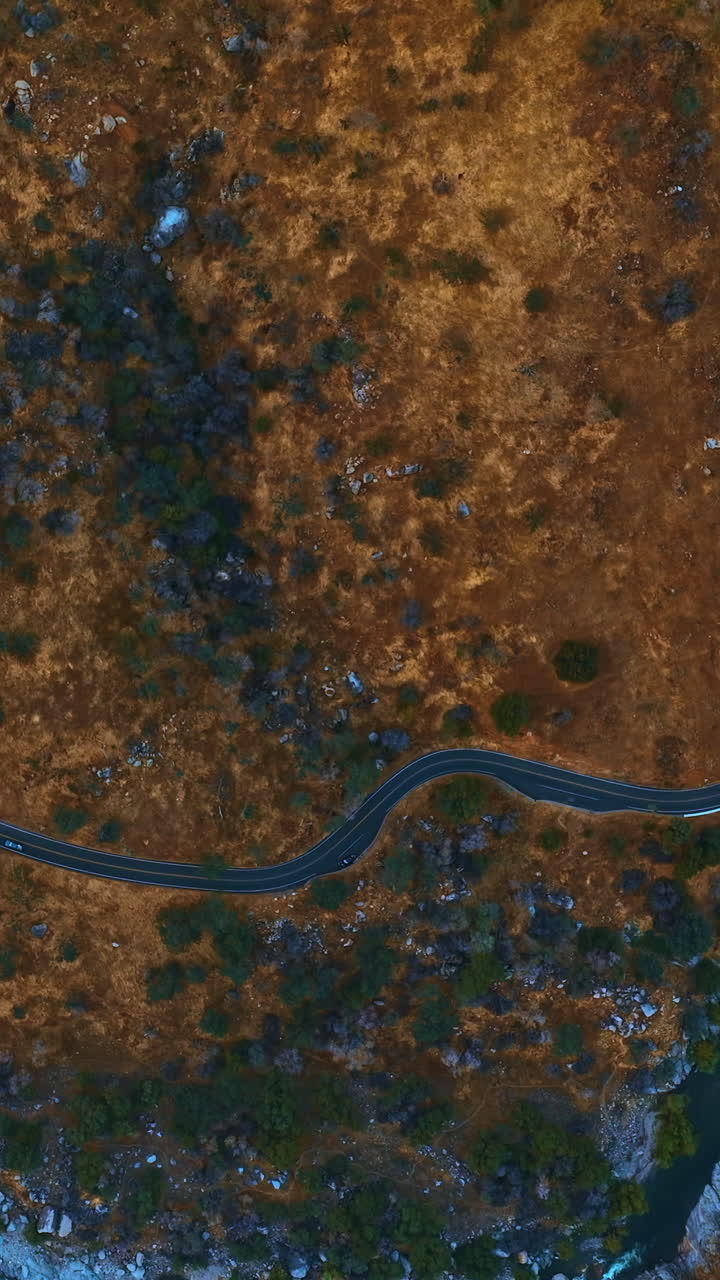 Wavy road in the mountainous area. Speed highway in dangerous place along the mountain river. Top view. Vertical video