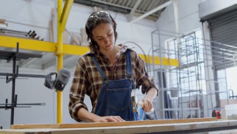 female welder hammering nail on a wooden plank 4k