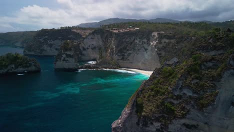 soaring drone footage highlights diamond beach bali as one of the most breathtaking coastal spots in indonesia with rugged cliffs, crystal waters, and bright sun illuminating the entire shoreline.