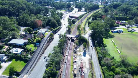 Querformatansicht-Eines-Zuges-Auf-Gleisen,-Der-An-Einer-Unterführungsbrücke-Vorbeiführt,-Ourimbah,-Hauptstadt-Der-Vororte,-Central-Coast,-Australien,-Transport,-Tourismus,-Drohnenluftaufnahme