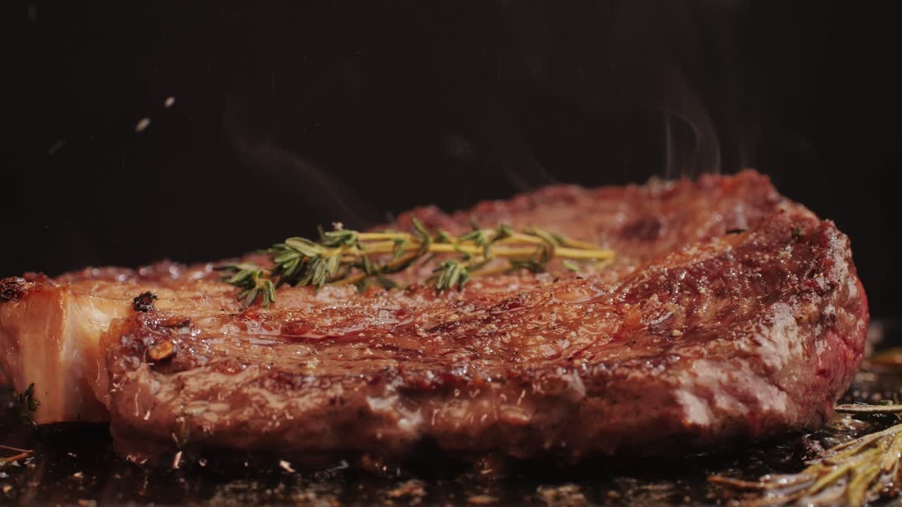 Fresh marbled beef with pepper, salt and rosemary close-up macro. Cooking juicy steak on grill with oil. Premium organic wagyu meat. High quality 4k footage