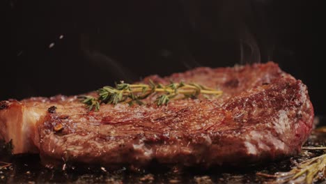 fresh marbled beef with pepper, salt and rosemary close-up macro. cooking juicy steak on grill with oil. premium organic wagyu meat. high quality 4k footage