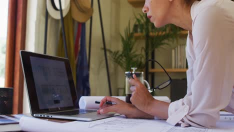 mujer caucásica usando una computadora portátil, trabajando desde casa