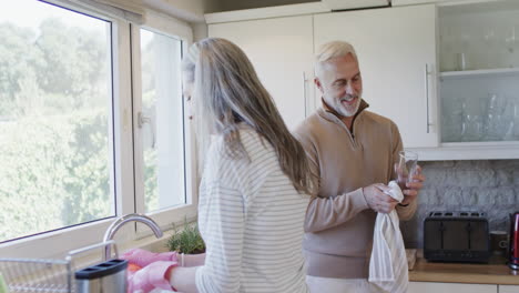 Pareja-Caucásica-De-Mediana-Edad-Lavándose-En-La-Cocina-Con-Espacio-Para-Copiar