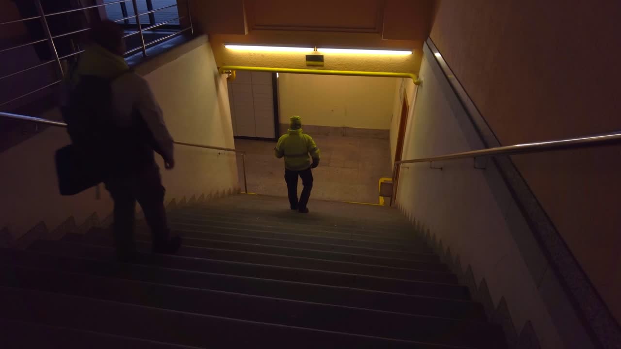 Commuter Men In Public Walking Downstairs Into Dark Underground Train Station In City In Czech Republic