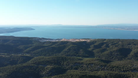 Wald-Auf-Hügeln-Mit-Einem-Steinbruchabbau-Und-Dem-Mittelmeer-Im-Hintergrund