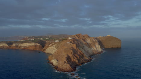 drone panning shot of akrotiri lighthouse in santorini, greece during sunset