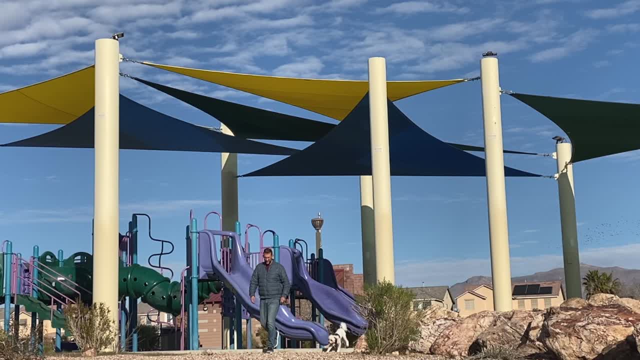 태양 아래 지역 공원에서 흰 개를 산책시키는 남자, 여전히 슬로우 모션 촬영