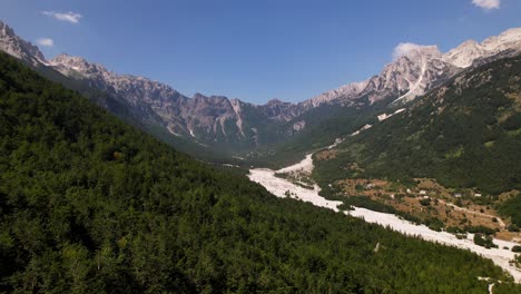 great valley of valbona national park, riverbed surrounded by green forest trees and high mountains