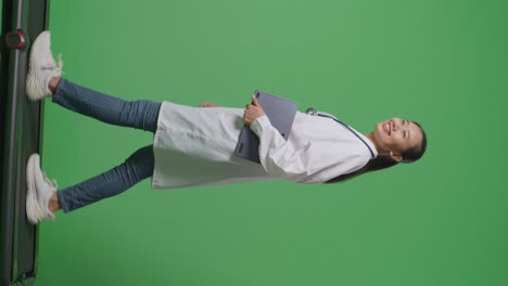 아시안 여성 의사가 스테토스코프를 들고 병원에서 녹색 화면 배경에서 는 동안 태블릿을 들고 있습니다.