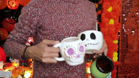 skull themed mugs being placed on day of the dead decorated altar