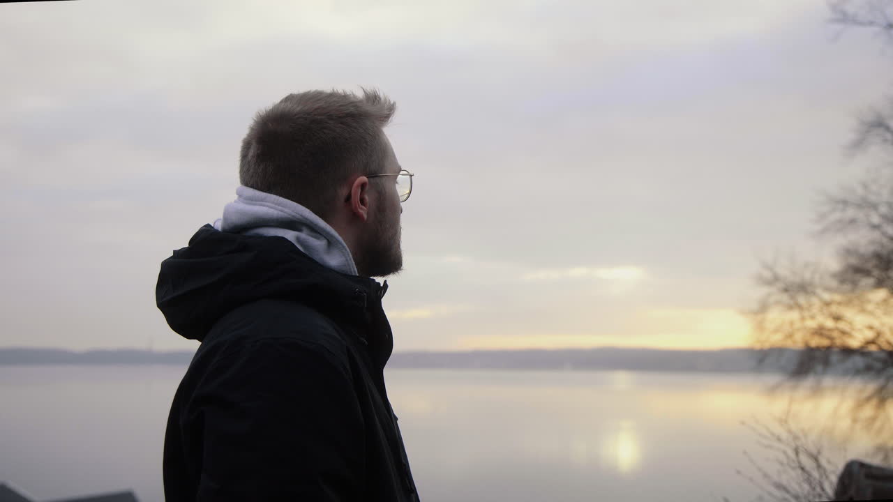 joven varón caucásico bebiendo café caliente de una taza sostenible fuera de vidrio